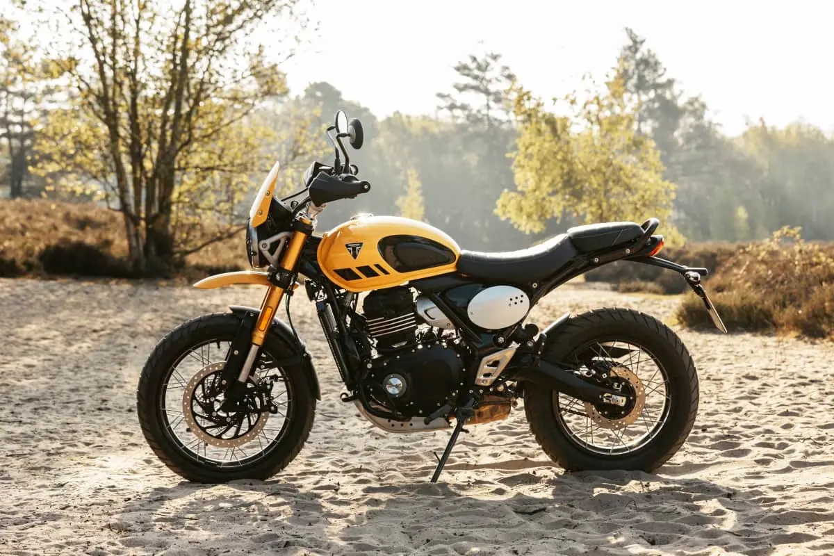 A yellow motorcycle parked on a dirt road